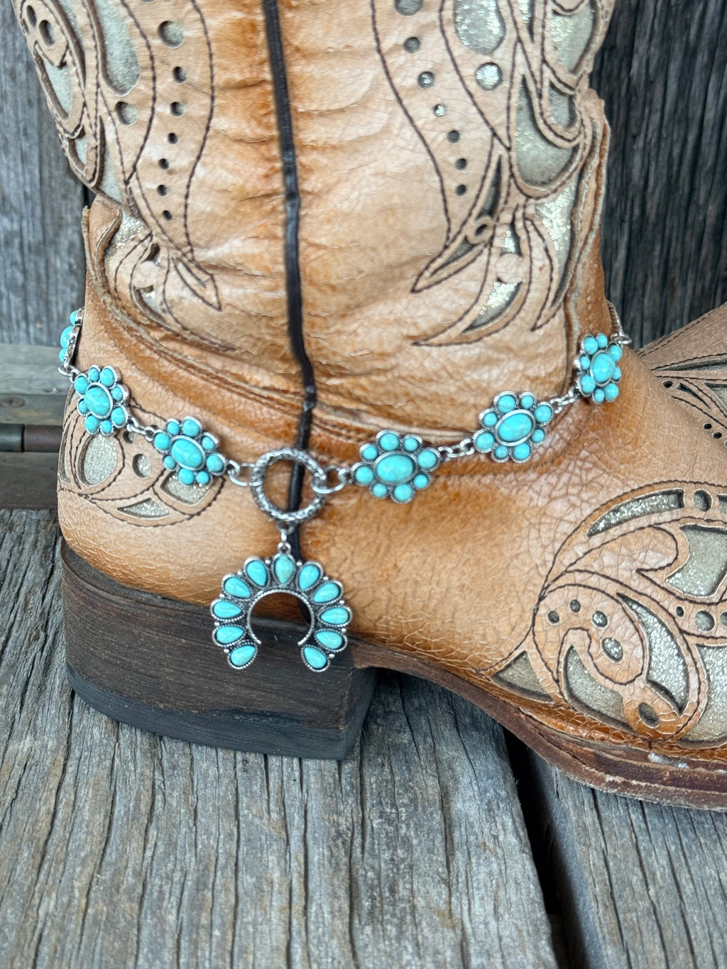 Close-up of turquoise squash blossom naja pendant dropping from silver toggle ring on 6-station boot bracelet chain
