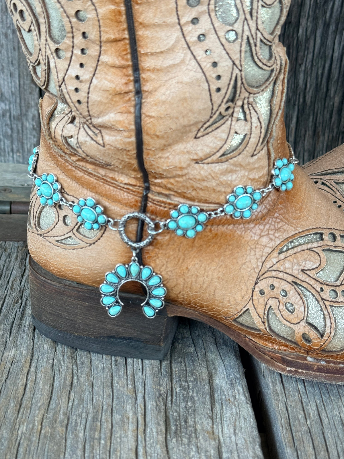 Close-up of turquoise squash blossom naja pendant dropping from silver toggle ring on 6-station boot bracelet chain
