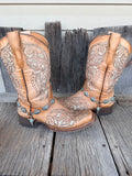 Turquoise concho and bull skull boot bracelet chain worn on tan tooled leather cowboy boots, full pair view
