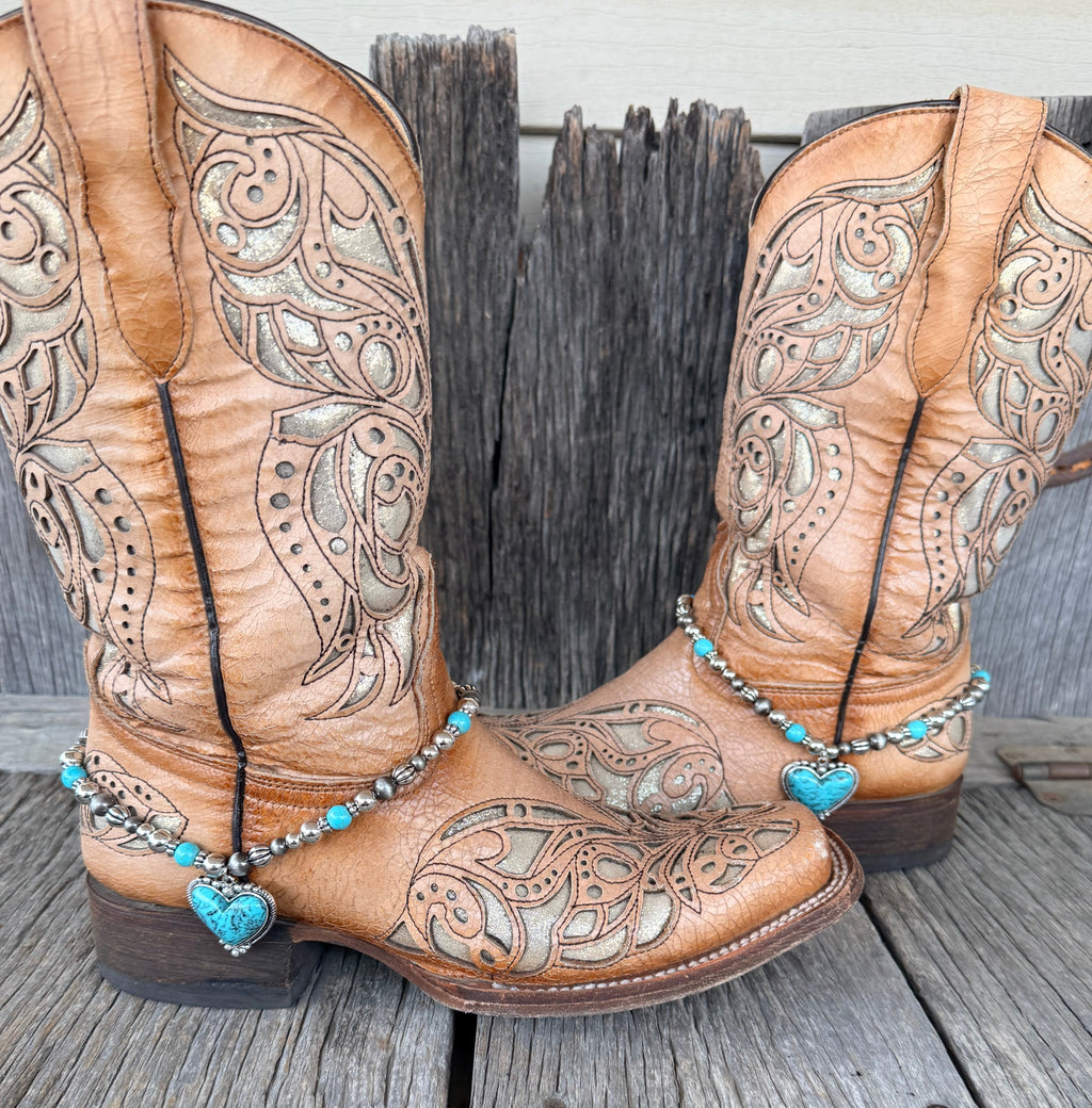 Turquoise heart and Navajo pearl silver beaded boot bracelet worn on tan tooled leather cowboy boots, full pair view
