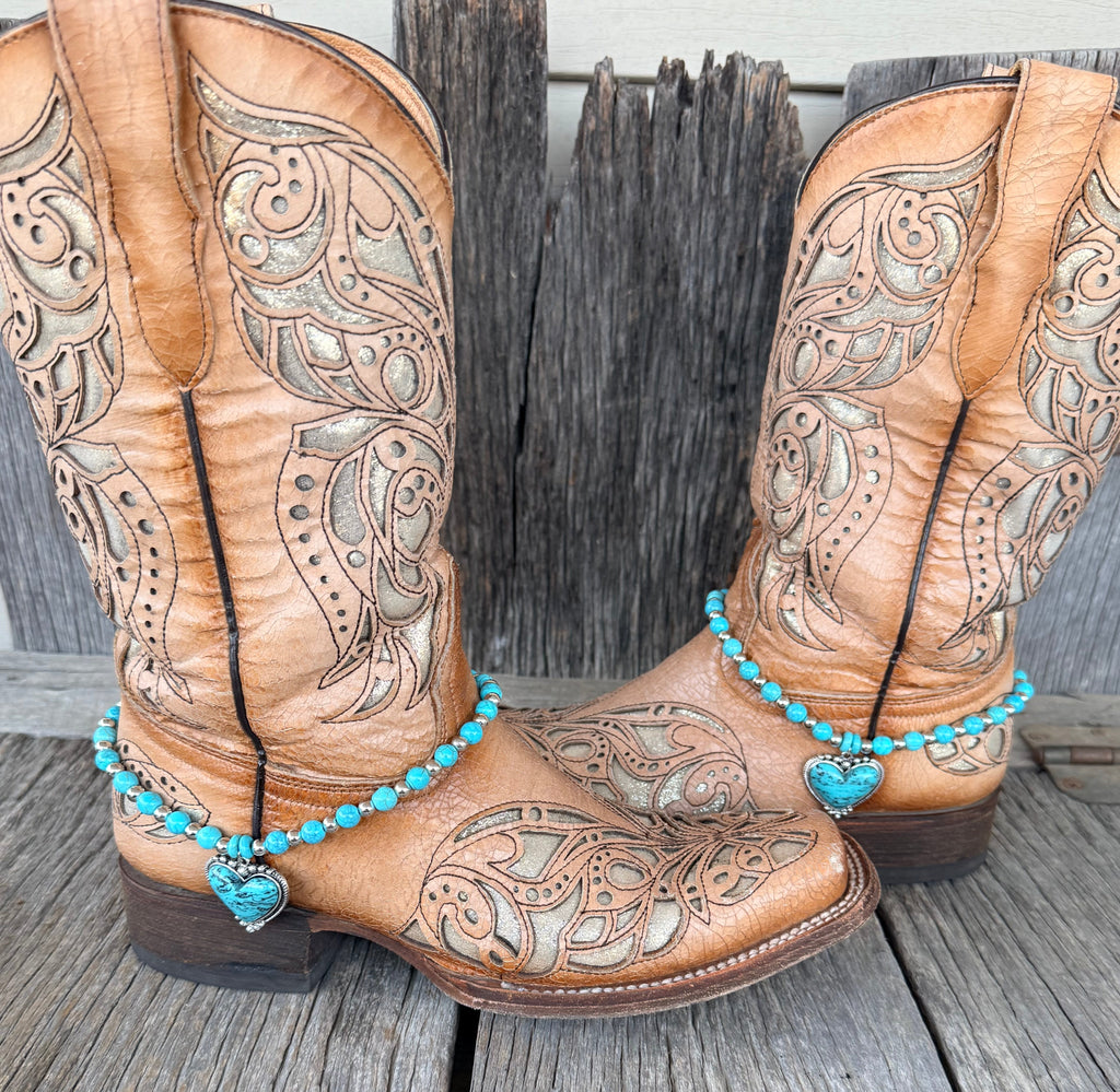 Turquoise beaded heart boot bracelet worn on tan tooled leather cowboy boots, full pair view
