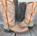 Turquoise beaded heart boot bracelet worn on tan tooled leather cowboy boots, full pair view
