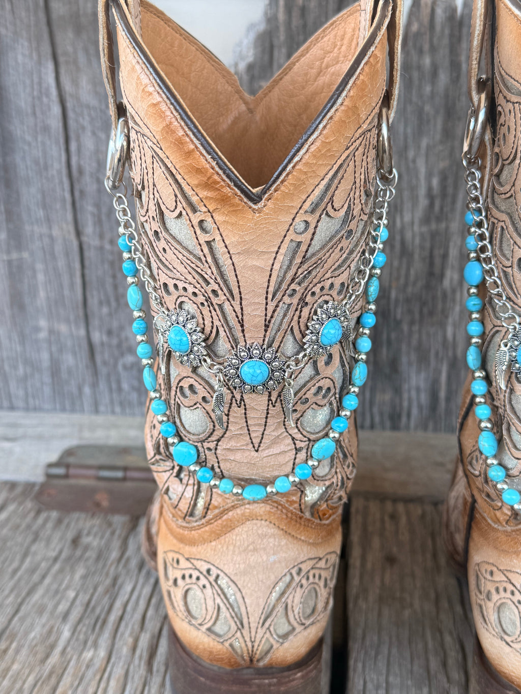 Close-up of large silver flower concho with turquoise cabochon center and flanking turquoise side conchos with feather drops on two-strand beaded boot bracelet chain
