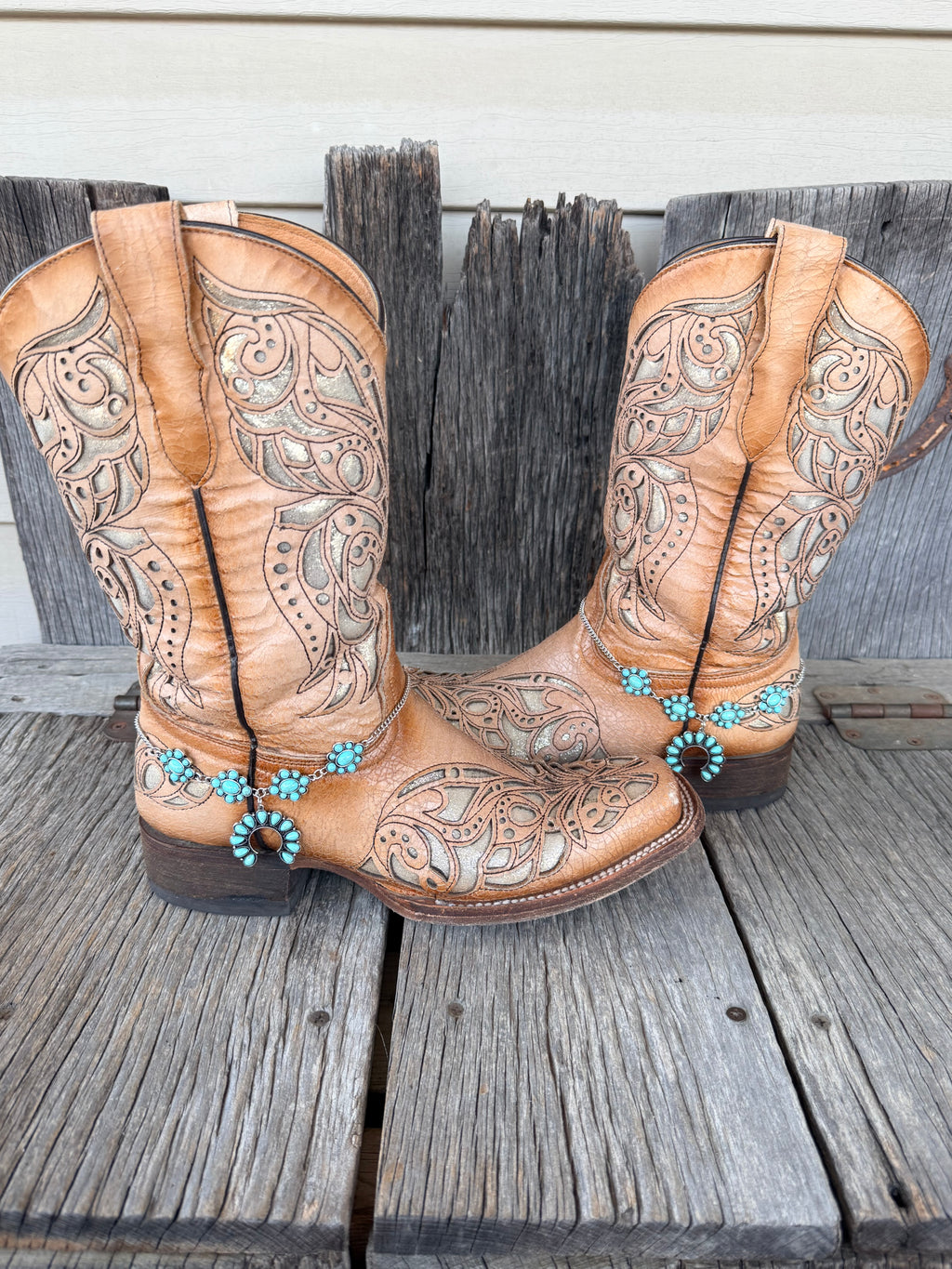 Turquoise squash blossom boot bracelet chain worn on tan tooled leather cowboy boots, full pair view
