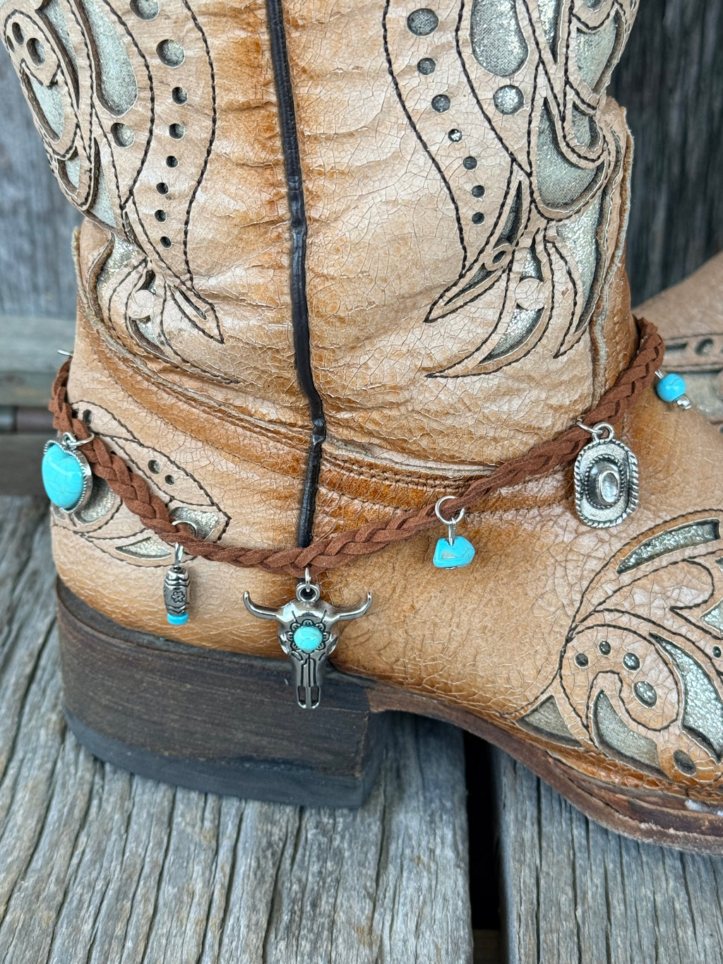 Close-up of bull skull centerpiece charm with turquoise heart beads and concho detail on braided leather strap
