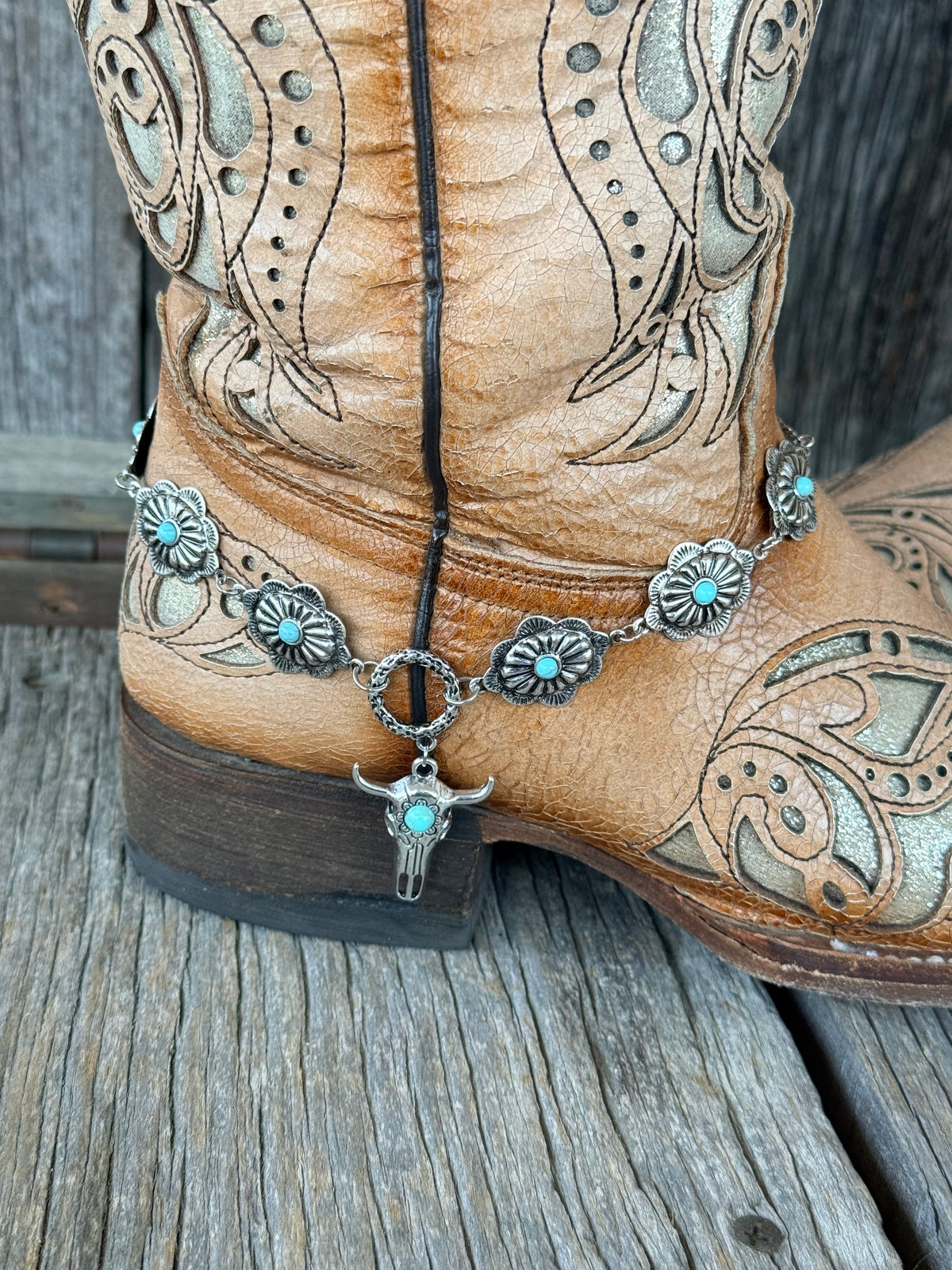 Close-up of silver bull skull pendant with turquoise accent dropping from toggle ring on turquoise concho boot bracelet chain
