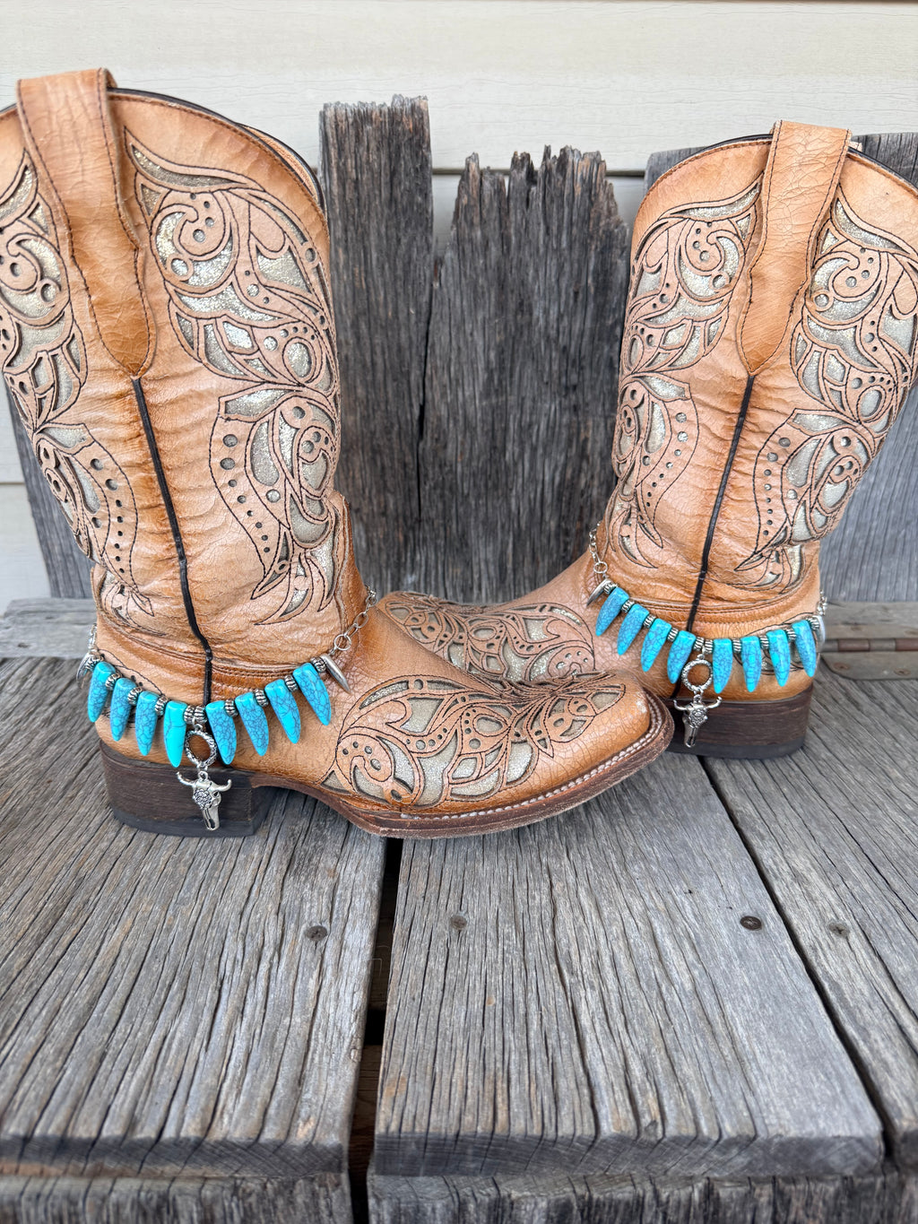 Turquoise coyote tooth and bull skull boot bracelet worn on tan tooled leather cowboy boots, full pair view
