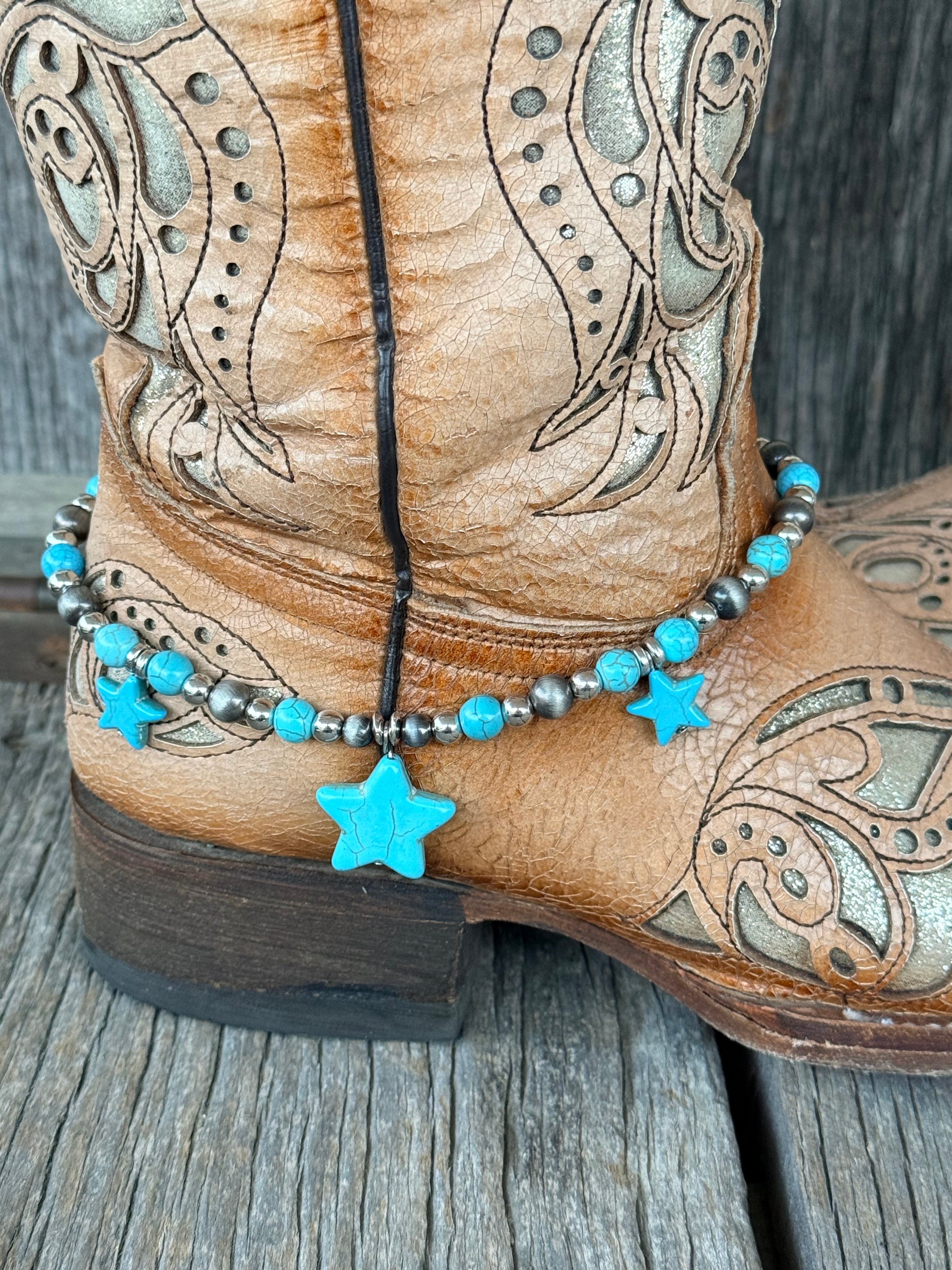 Close-up of Navajo pearl silver round bead and turquoise bead boot bracelet with large center turquoise star stone pendant and two smaller flanking turquoise stars at heel of tan tooled cowboy boot
