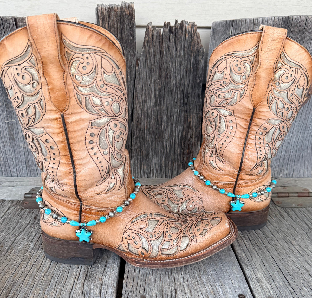 Turquoise star and Navajo pearl boot bracelet with large turquoise star stone pendant and teardrop accents worn on tan tooled laser-cut cowboy boots, full pair front view on wood surface
