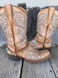 Braided leather boot bracelet with silver bull skull charm and turquoise heart beads, styled on cowboy boots
