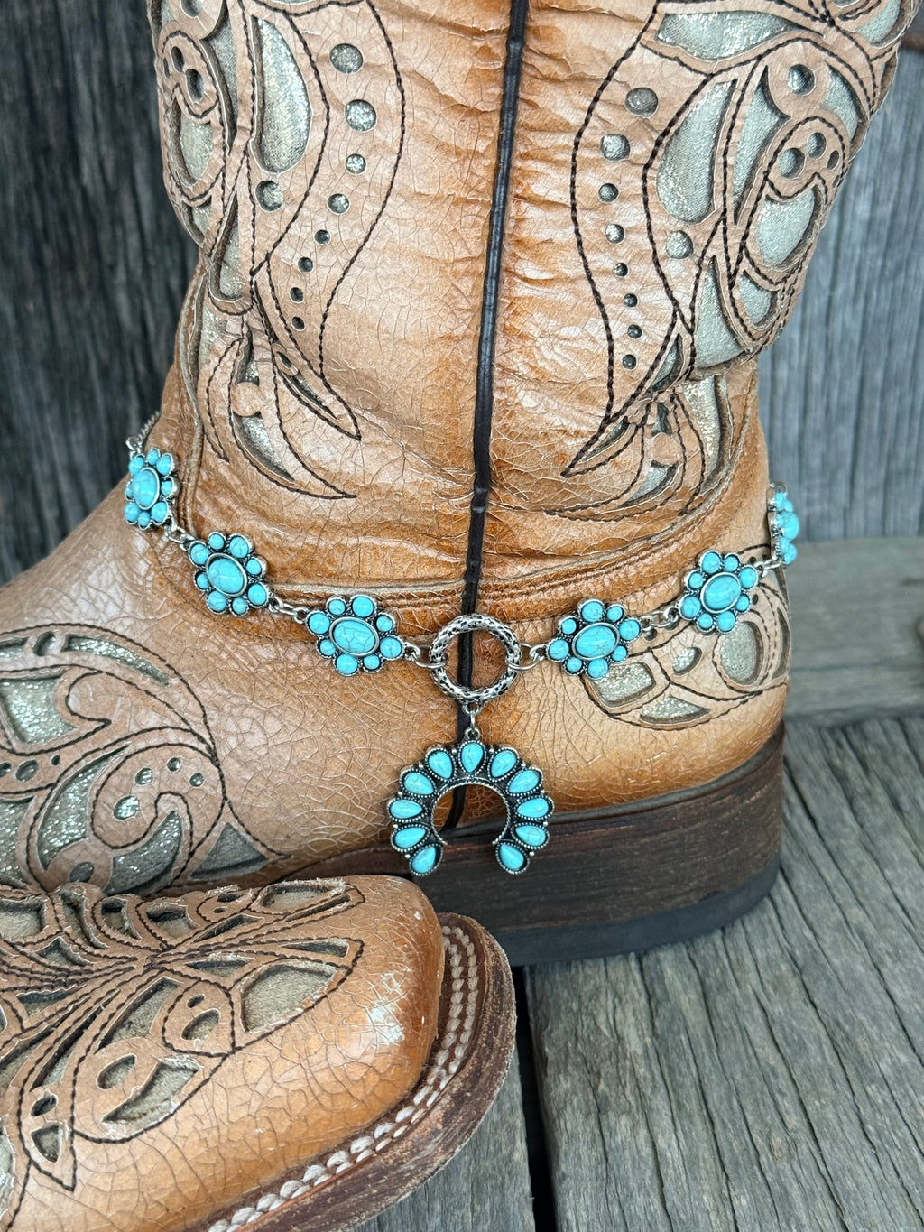 Side angle of turquoise cluster rosette 6-station boot bracelet chain draped along tan tooled leather cowboy boot shaft
