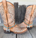 Turquoise and silver beaded boot bracelet with large silver angel wing pendant worn on tan tooled leather cowboy boots, full pair view
