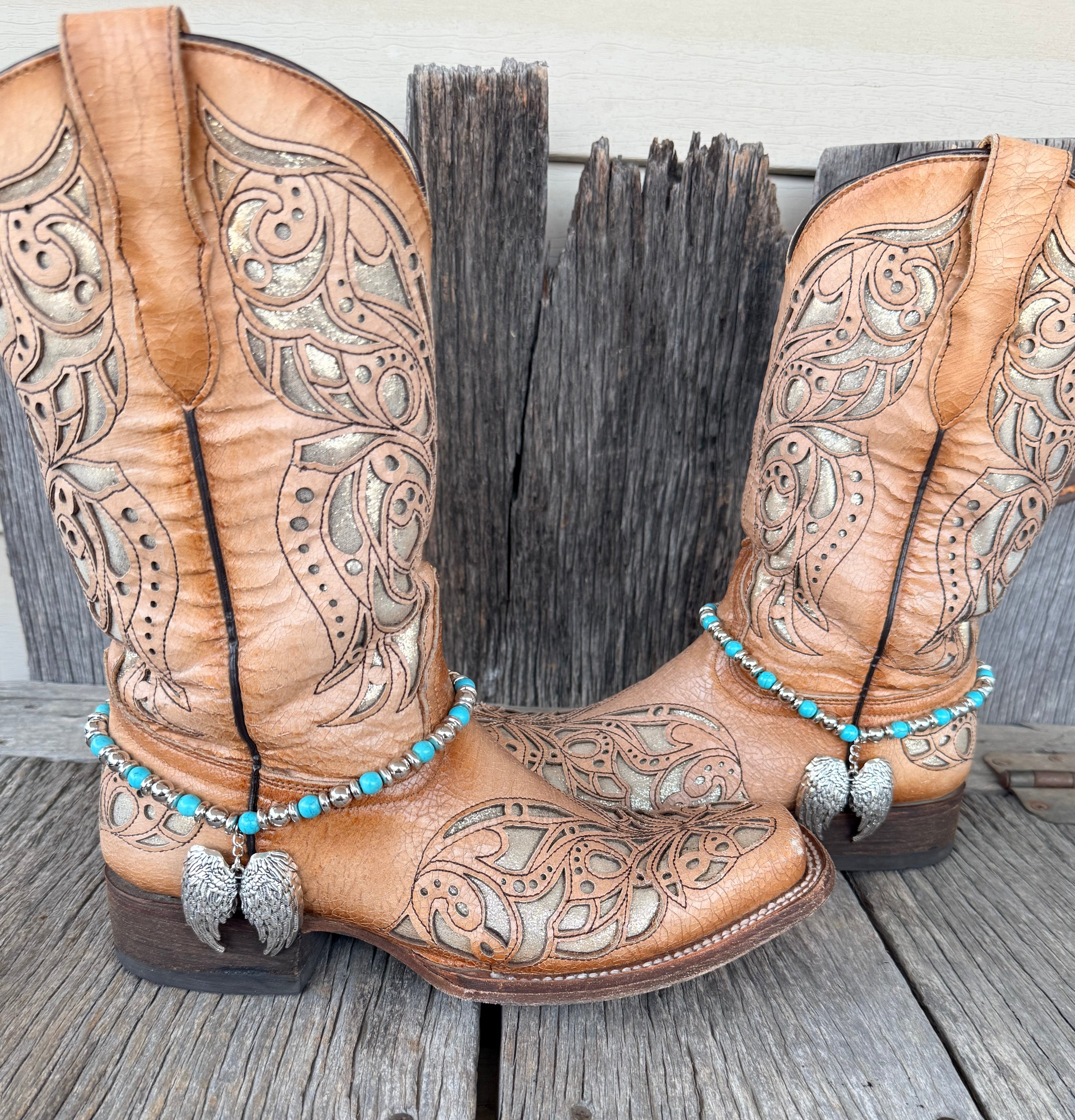 Turquoise and silver beaded boot bracelet with large silver angel wing pendant worn on tan tooled leather cowboy boots, full pair view
