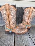 Turquoise and silver beaded boot bracelet with lightning bolt pendant worn on tan tooled leather cowboy boots, full pair view
