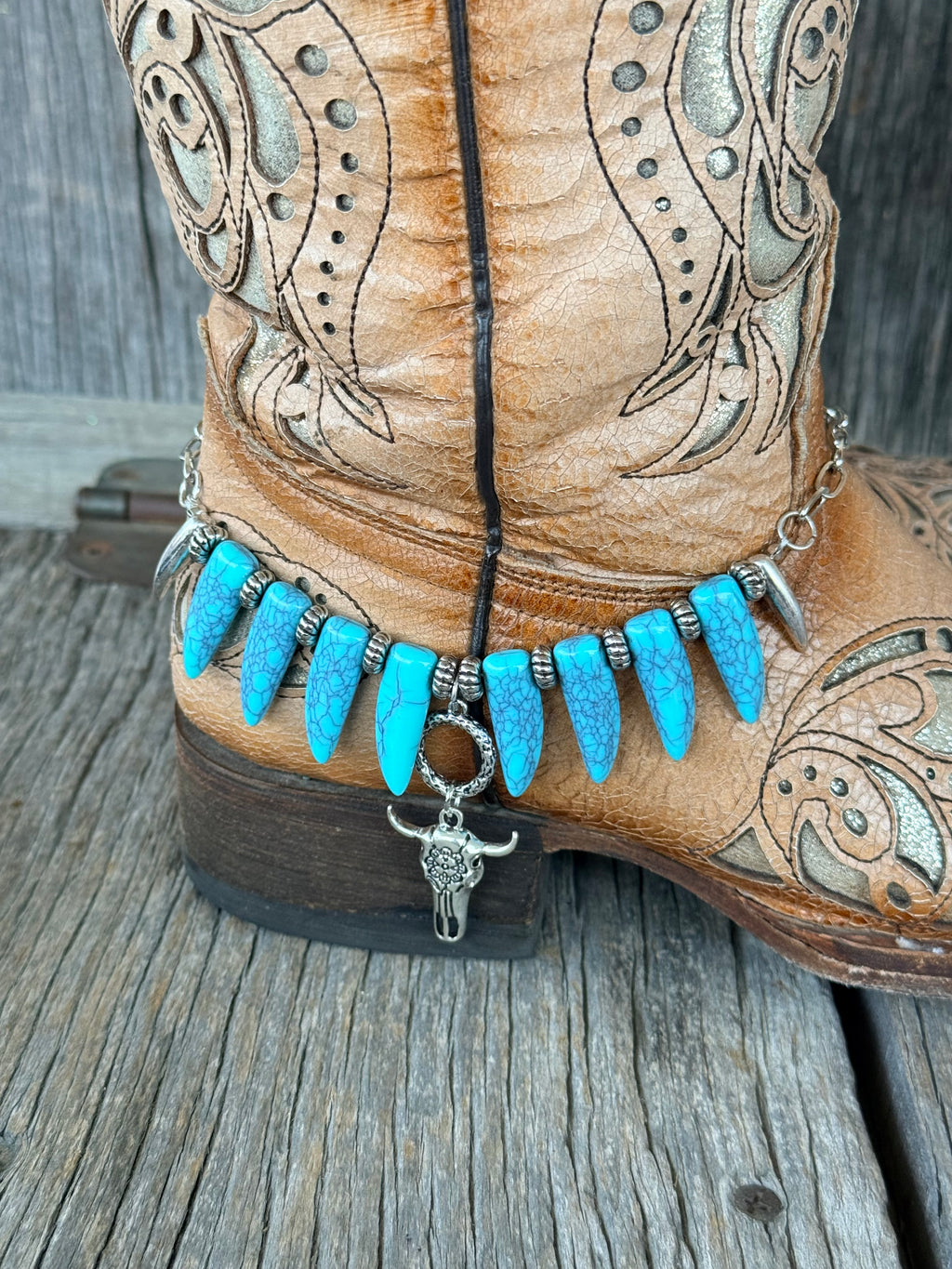 Close-up of turquoise coyote tooth beads with silver rondelle spacers and bull skull pendant dropping from snake ring toggle on boot bracelet
