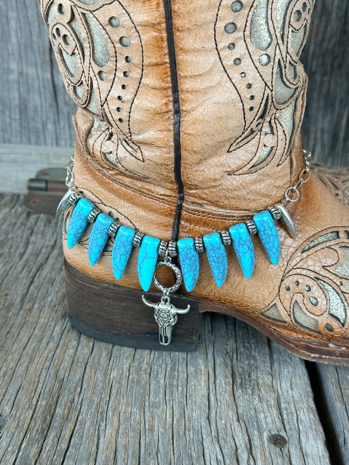 Close-up of turquoise coyote tooth beads with silver rondelle spacers and bull skull pendant dropping from snake ring toggle on boot bracelet
