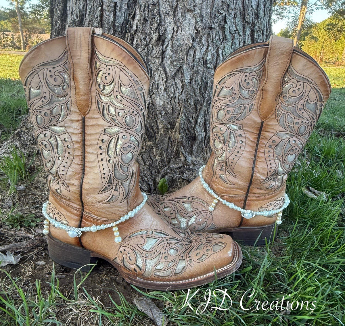 Pair of tan tooled leather cowboy boots leaning against a tree wearing pearl and crystal beaded boot bracelets with rhinestone concho centerpiece, set of 2, KJD Creations