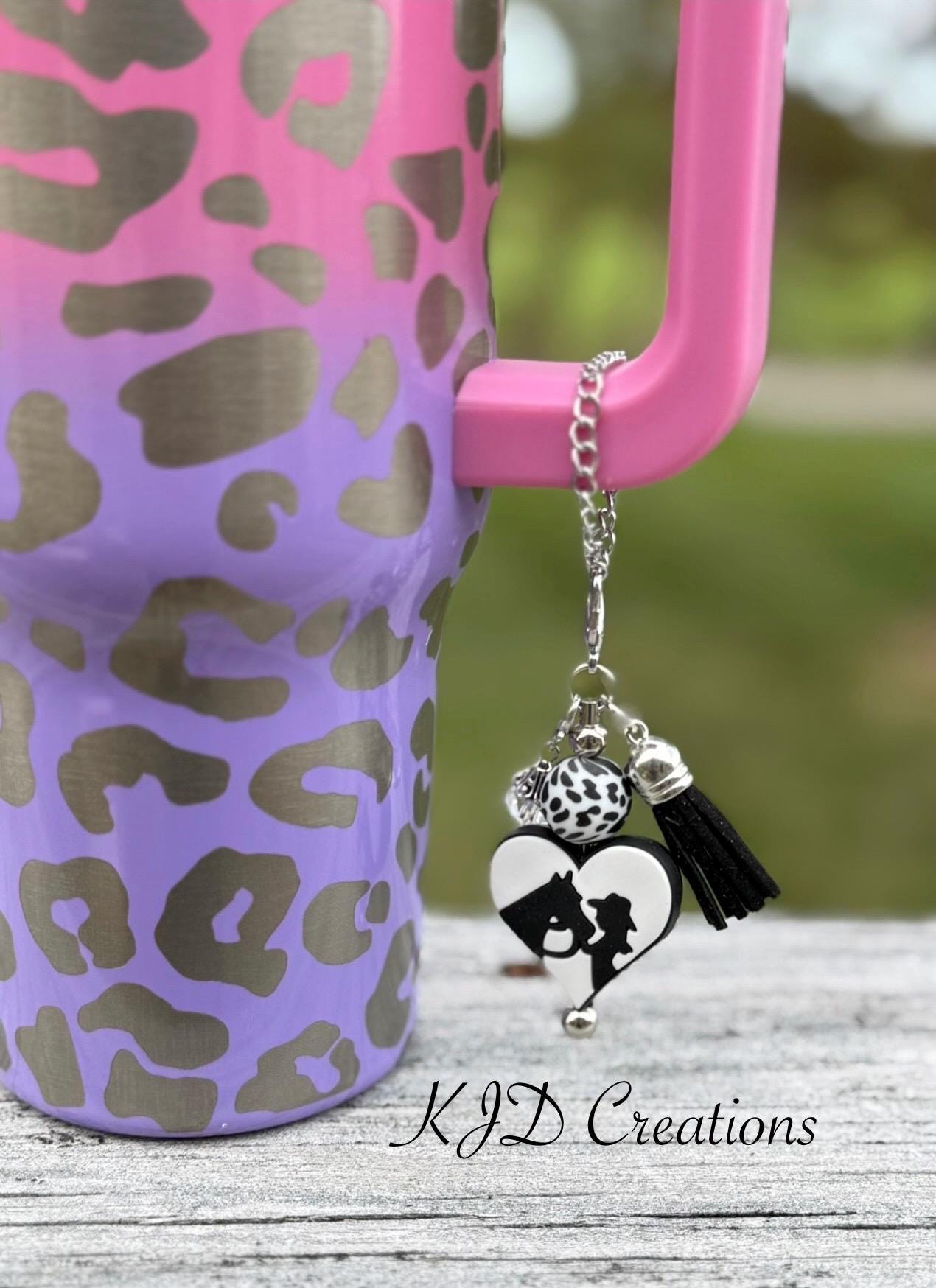 Cowgirl Horse Western tumbler cup handle charm clipped to a pink and purple leopard print insulated tumbler — black and white heart with cowgirl silhouette, cow print bead, and black tassel by KJD Creations