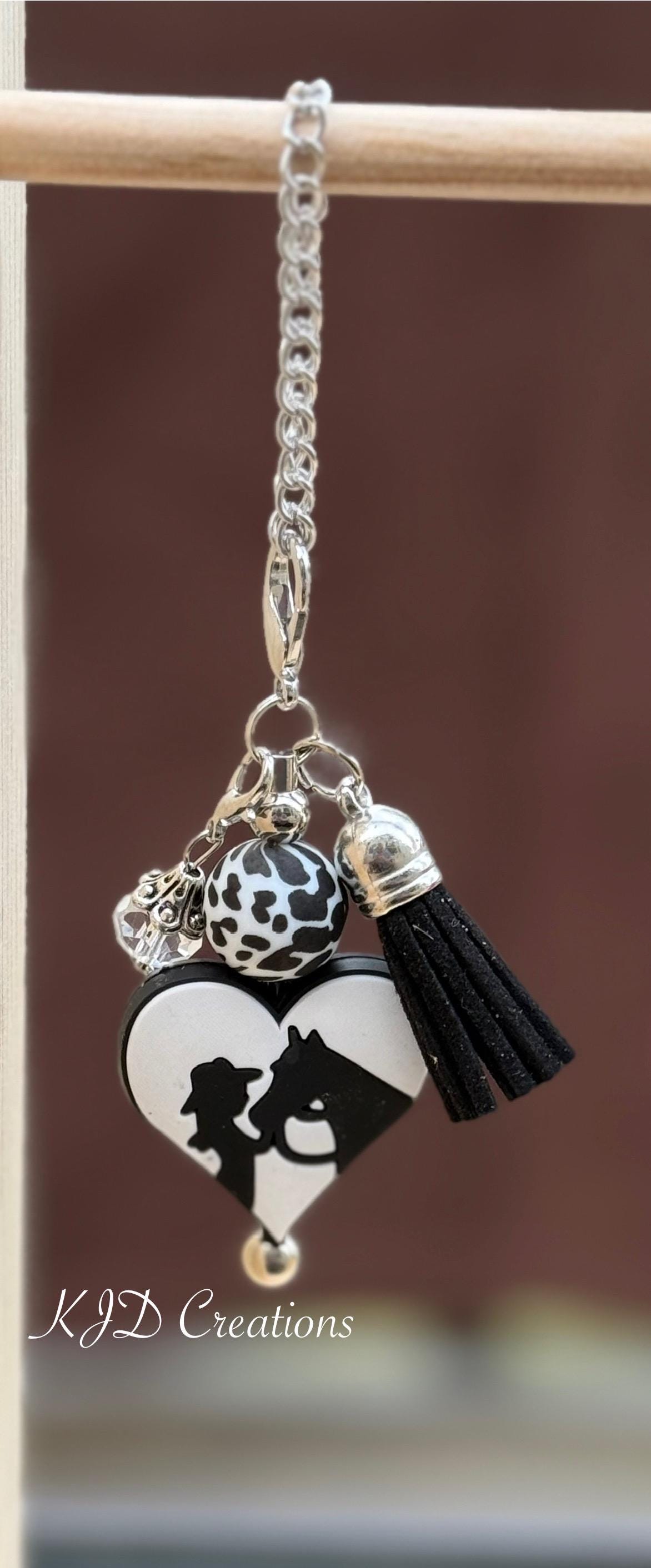 Cowgirl Horse Western tumbler cup handle charm clipped to a pink and purple leopard print insulated tumbler — black and white heart with cowgirl silhouette, cow print bead, and black tassel by KJD Creations