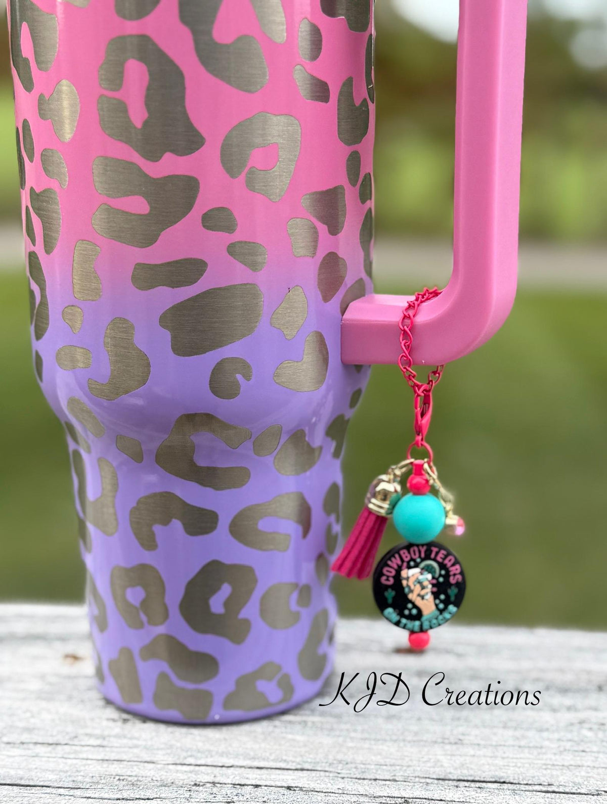 Cowboy Tears Western tumbler cup handle charm clipped to a leopard print insulated tumbler — black charm with teal bead and pink tassel by KJD Creations