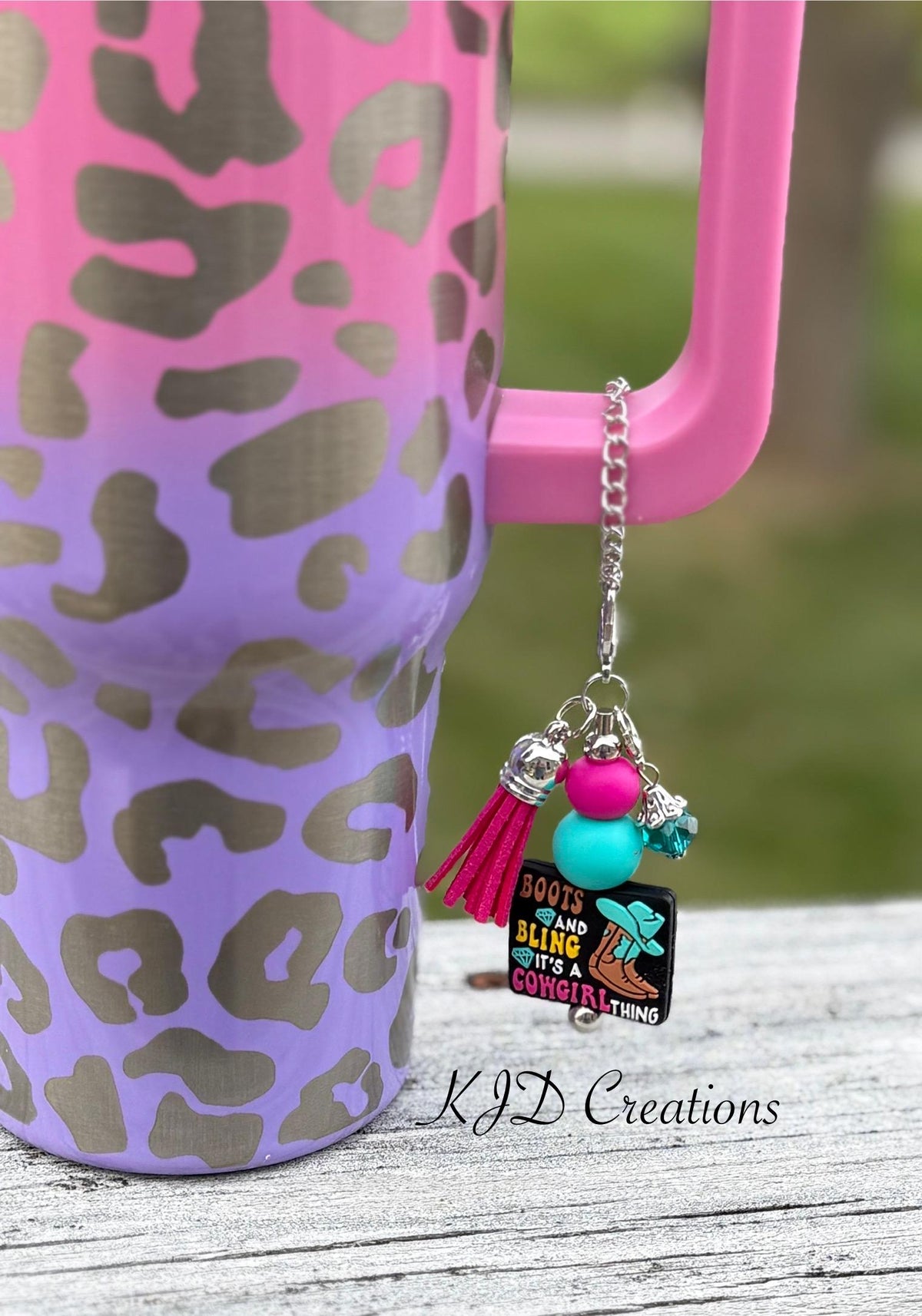 Boots Bling Western tumbler cup handle charm clipped to a pink and purple leopard print insulated tumbler — "Boots and Bling It's a Cowgirl Thing" black charm with hot pink and teal beads and pink tassel by KJD Creations