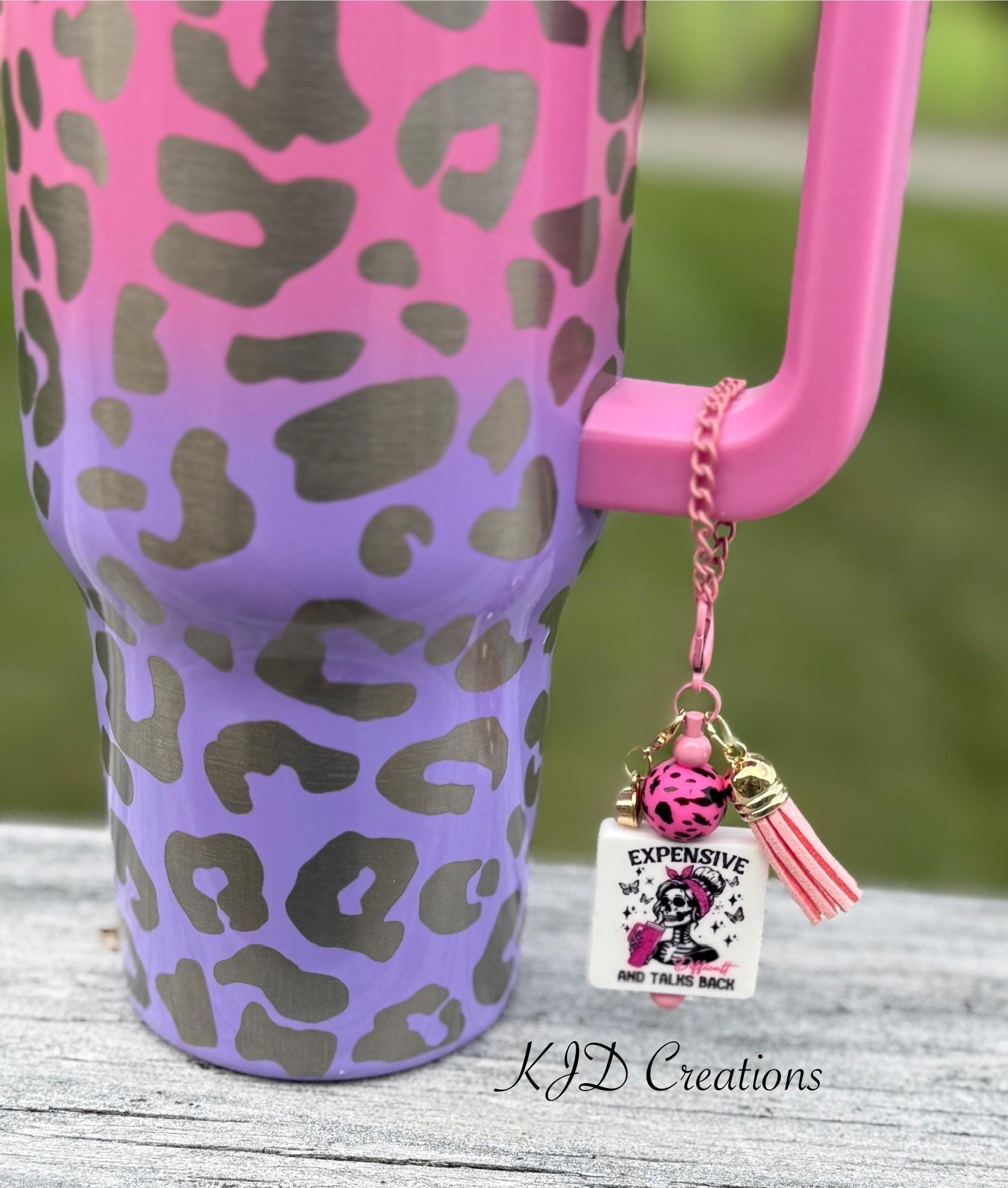 Funny silicone beaded tumbler cup charm with "Expensive and Talks Back" pendant, pink leopard bead, and pink leather tassel on pink chain, clipped to a pink and purple leopard print tumbler