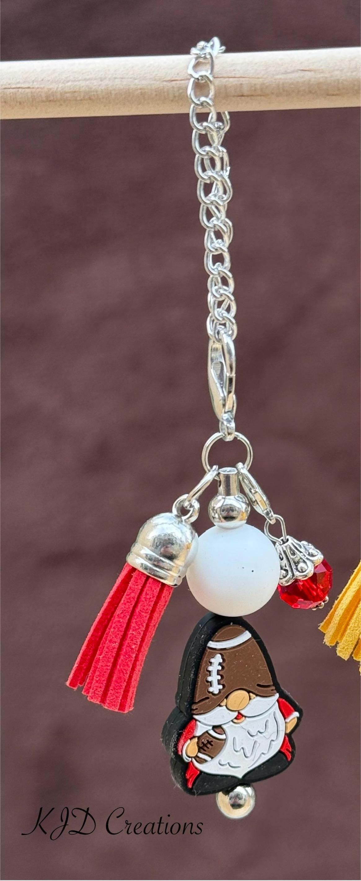 Football Gnome tumbler dangle charm close-up on display rack — silver chain with white bead, red leather tassel, and football gnome holding a football charm by KJD Creations