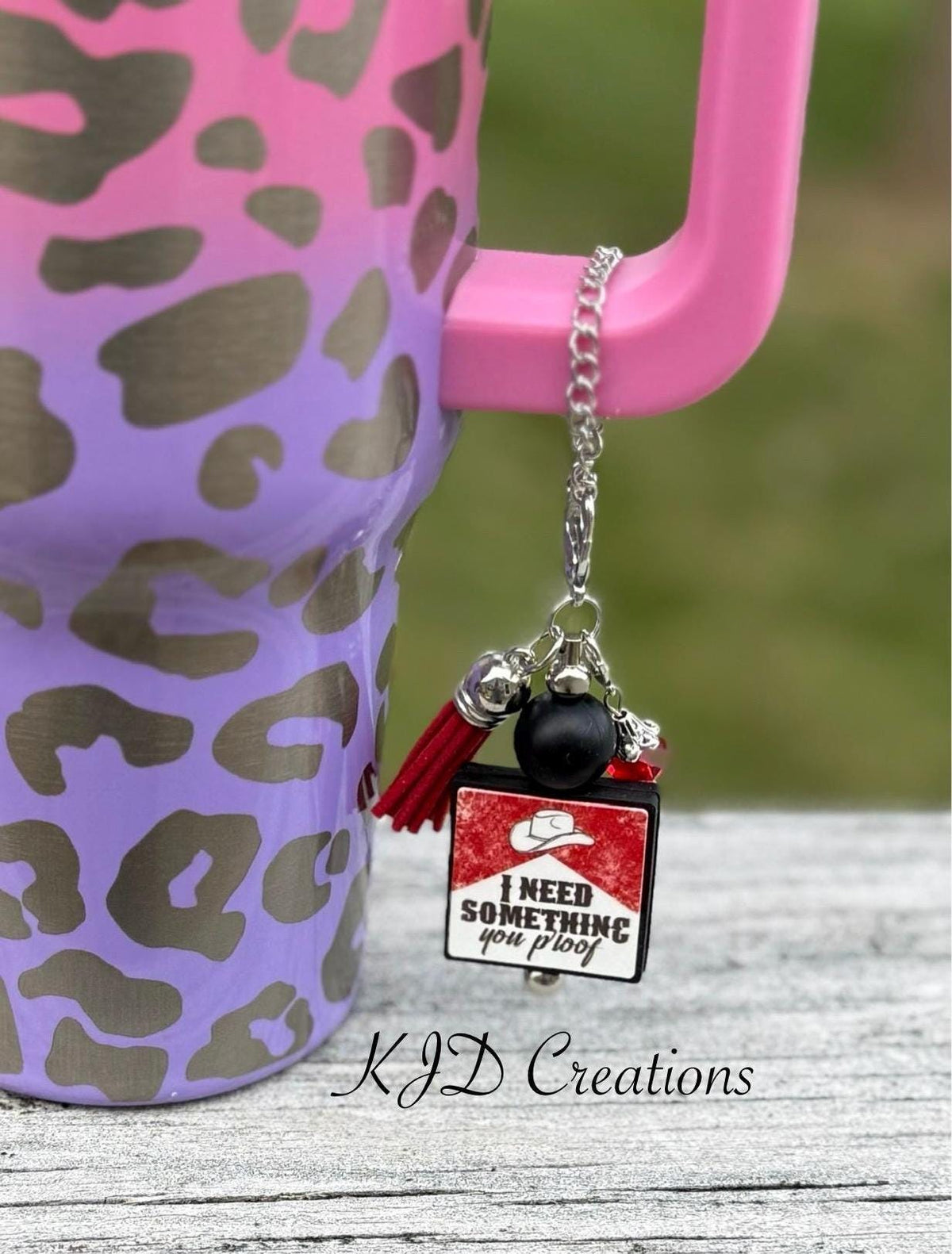 You Proof country music tumbler cup handle charm clipped to a pink and purple leopard print insulated tumbler — black bead with red tassel and cowboy hat 