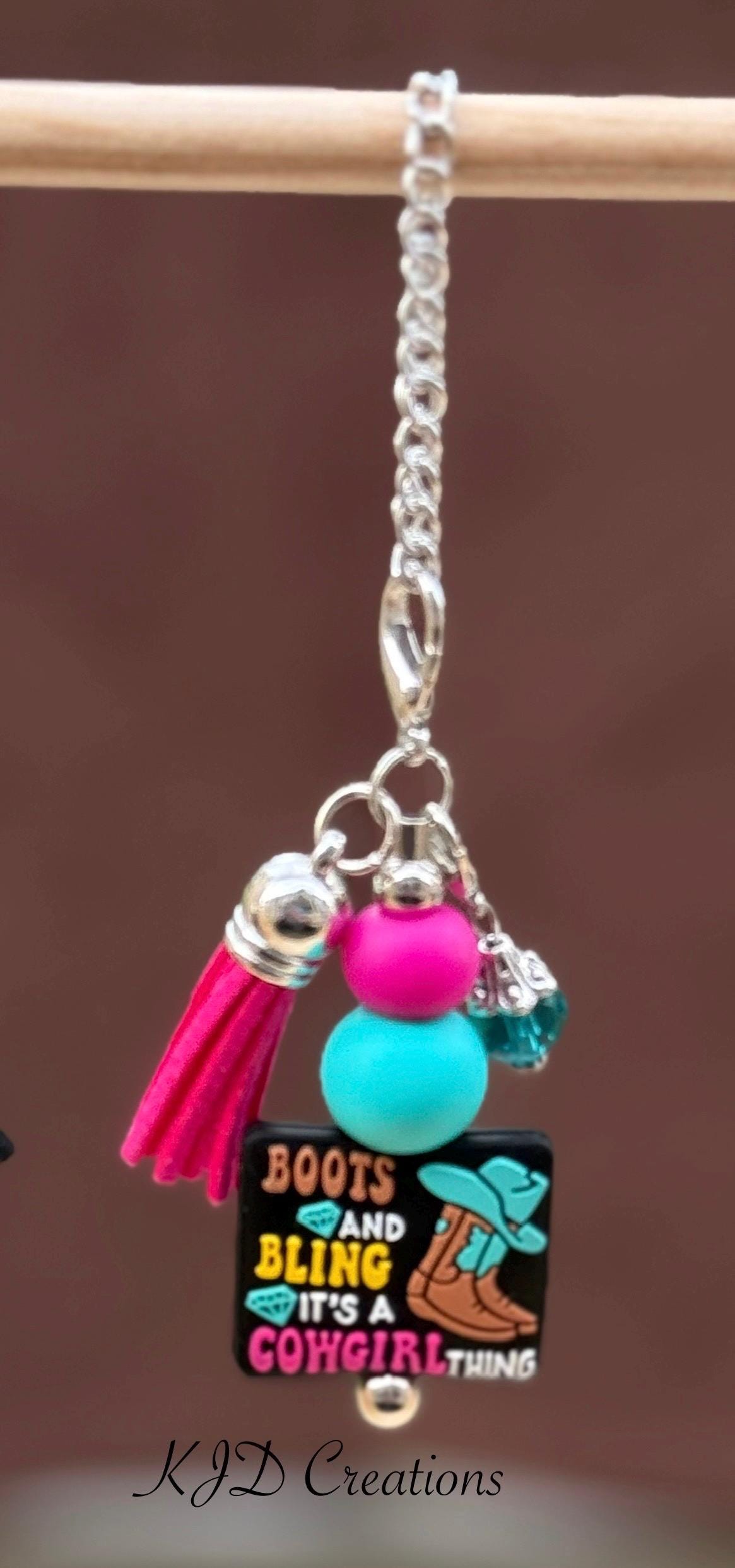 Boots Bling Western tumbler cup handle charm on a display rack — "Boots and Bling It's a Cowgirl Thing" black charm with hot pink and teal beads and pink tassel by KJD Creations