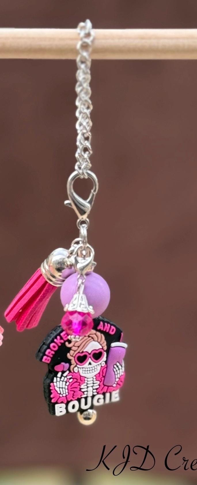 Broke and Bougie pink silicone beaded tumbler cup charm with sassy skull pendant, pink silicone bead, and hot pink leather tassel on silver chain, on a display rack
