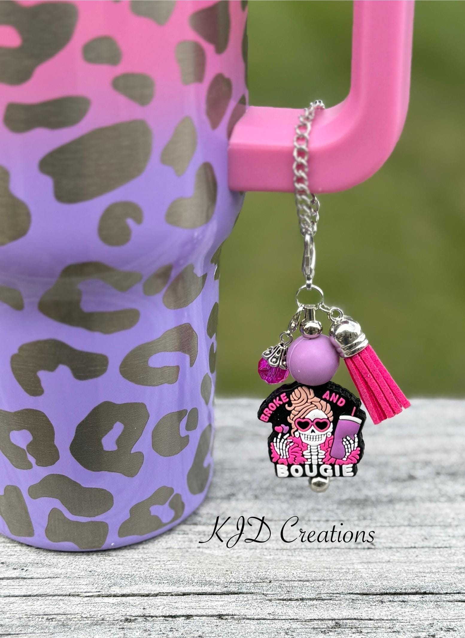 Broke and Bougie pink silicone beaded tumbler cup charm with sassy skull pendant, pink silicone bead, and hot pink leather tassel on silver chain, clipped to a purple leopard print tumbler
