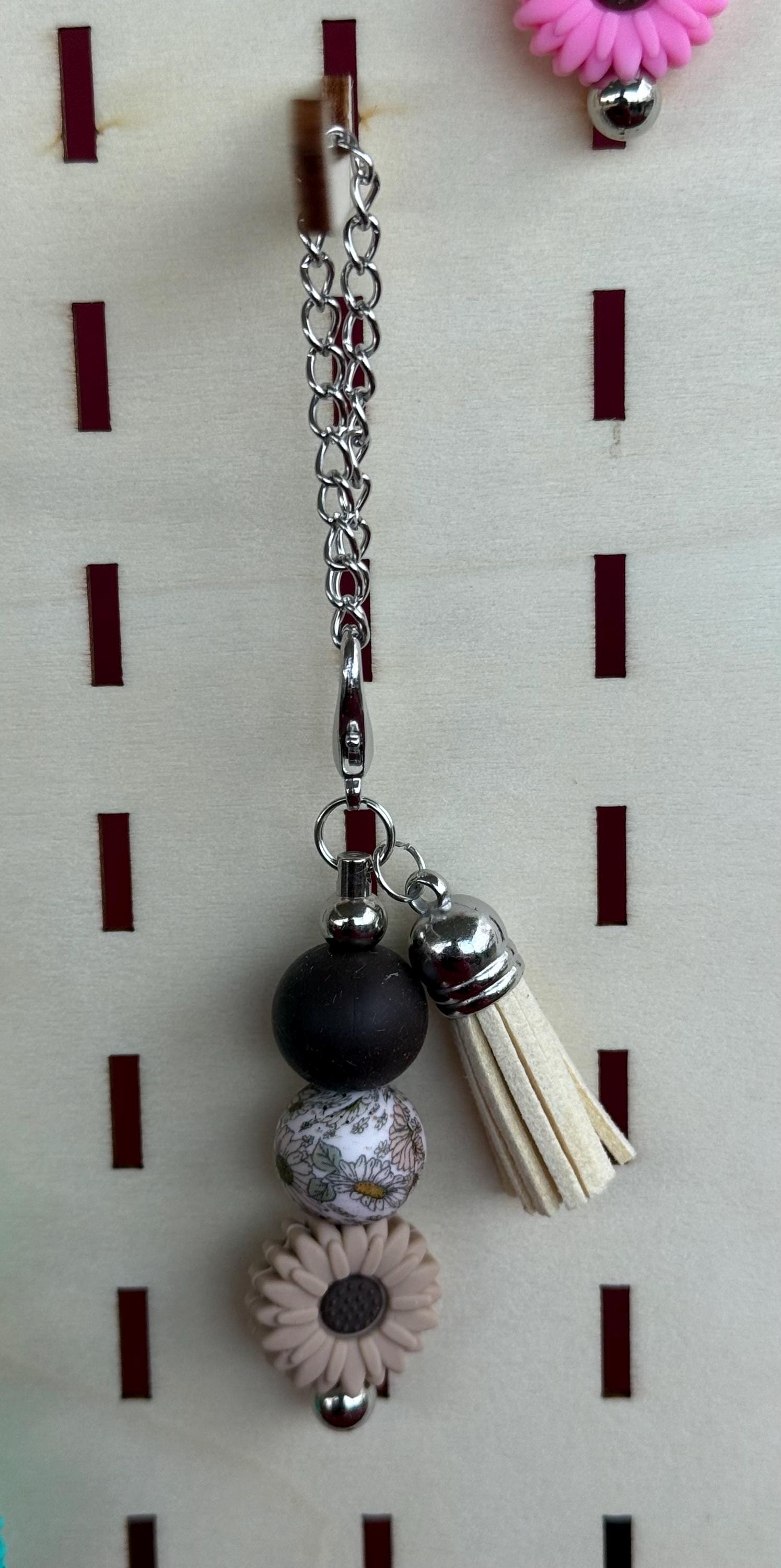 Gray western boho beaded tumbler cup charm with black bead, floral bead, gray daisy, and cream tassel on silver chain