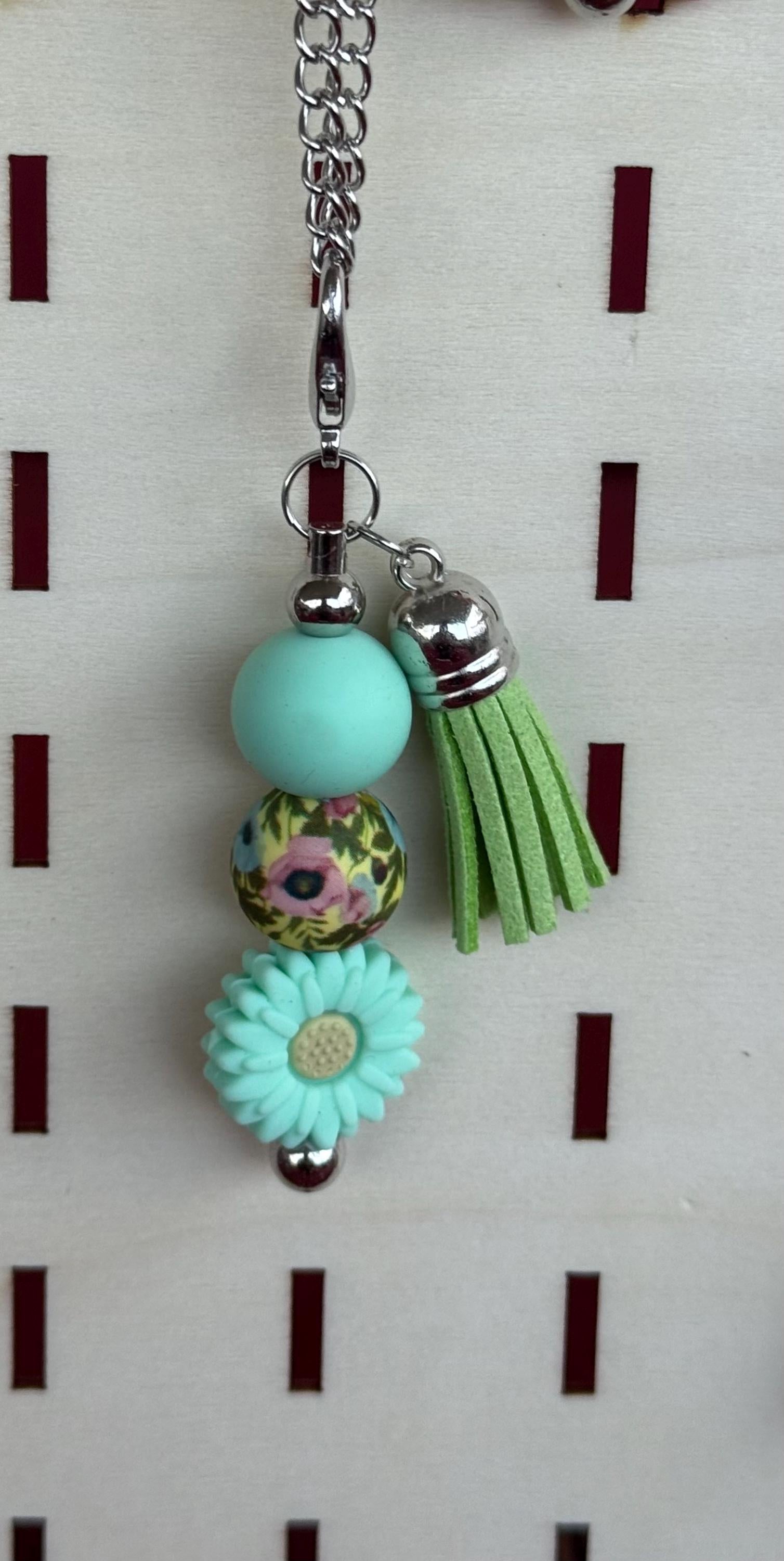 Turquoise western boho beaded tumbler charm with floral bead, teal daisy, and green tassel on silver chain