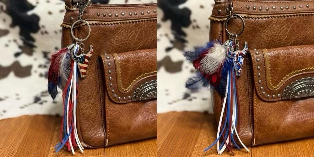 A brown leather handbag shown from the front with a decorative tassel keychain hanging from the front pocket. The tassel includes feathers and fringe in red, white, and blue, along with a small silver-toned emblem.