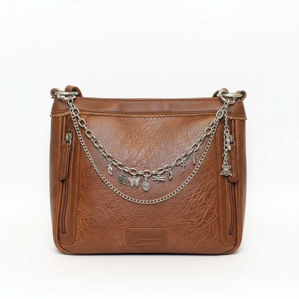 Alternate front view of tan distressed Bandana leather crossbody bag on cowhide rug with two-strand gold-tone oval link and curb chain purse necklace featuring seven gold charms, 11.5-inch Western boho handbag jewelry accessory