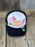 A black and white trucker hat with colorful embroidered patches, including 'YEEHAWS and HELLNAWS' in a peach box, resting on a rustic wooden surface.