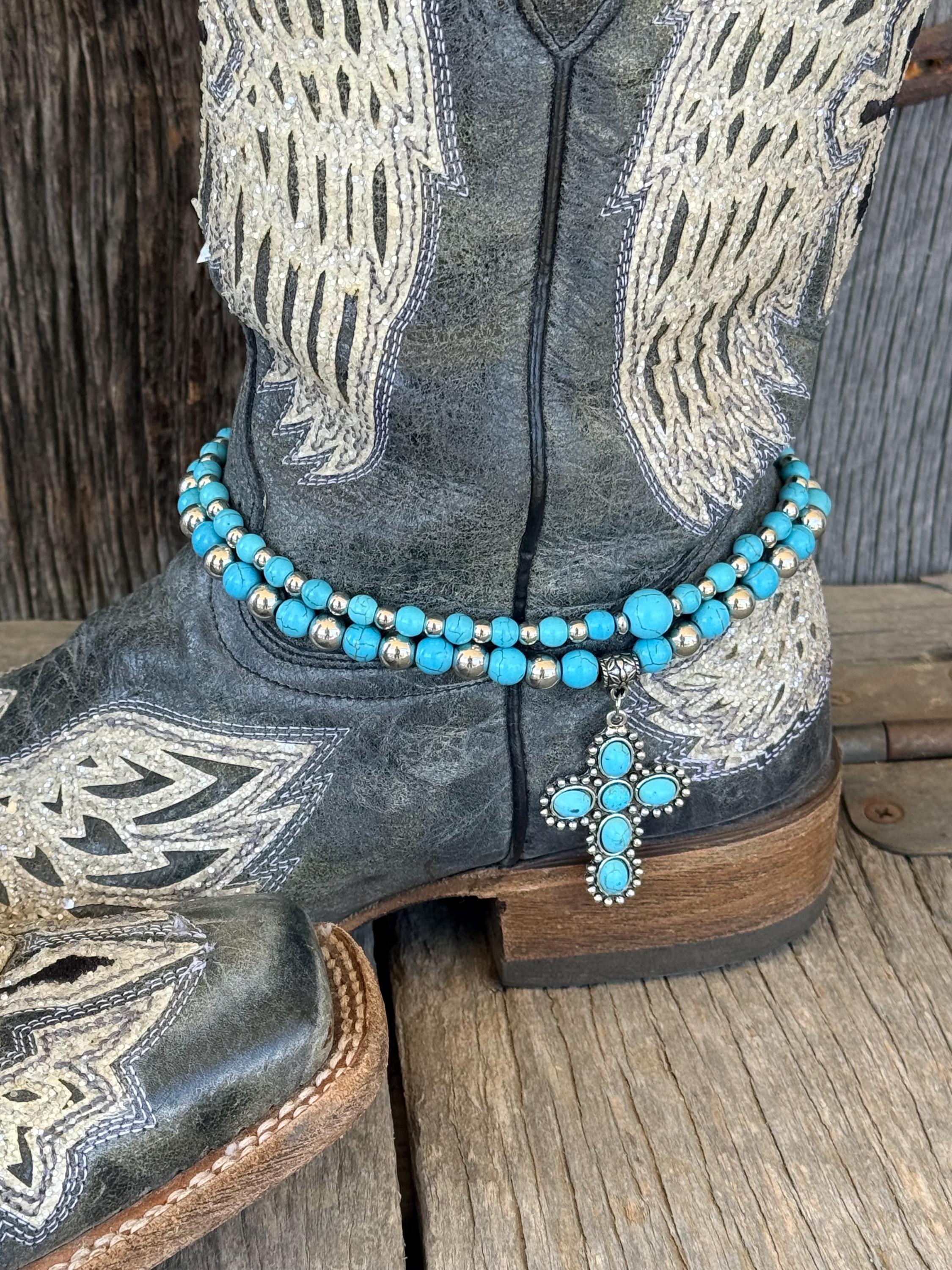 Wide shot of black angel wing cowboy boots styled with double-strand turquoise and silver beaded boot bracelets and turquoise cross charm pendants