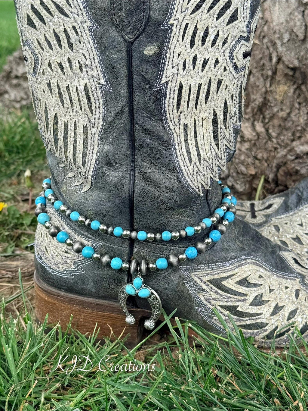 Close-up of black distressed angel wing cowboy boot ankle with two-strand turquoise and oxidized silver bead boot bracelet and silver filigree squash blossom naja pendant with three turquoise teardrop stones