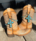 Pair of tan tooled leather cowboy boots on rustic wood planks wearing turquoise beaded boot bracelets with large silver turquoise cross concho charms, set of 2