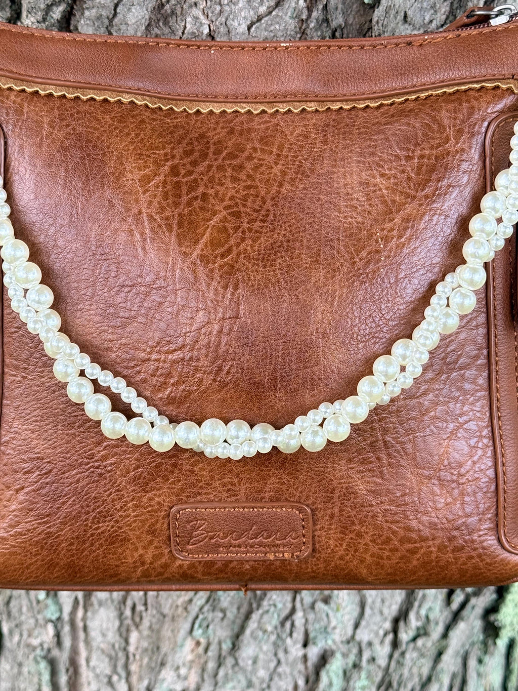 Close-up of brown leather Bandana crossbody bag with Western boho twisted faux pearl strand purse chain showing two twisted strands of larger round pearls alternating with smaller seed pearls in elegant rope-style construction, 16-inch Western handbag jewelry