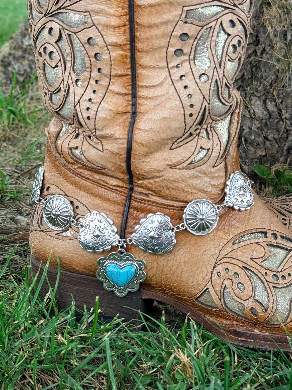 Front view of tan tooled laser-cut cowboy boot with silver concho chain boot bracelet and turquoise heart drop charm pendant, Western boho boot accessory