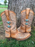 Front view of pair of tan tooled laser-cut cowboy boots against tree with silver multi-chain boot bracelets featuring two stacked turquoise oval concho charms, Western boho boot jewelry set of 2