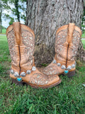 Front view of pair of tan tooled laser-cut cowboy boots against tree on grass wearing silver concho chain boot bracelets with turquoise heart drop charm pendant, Western boho boot jewelry set of 2