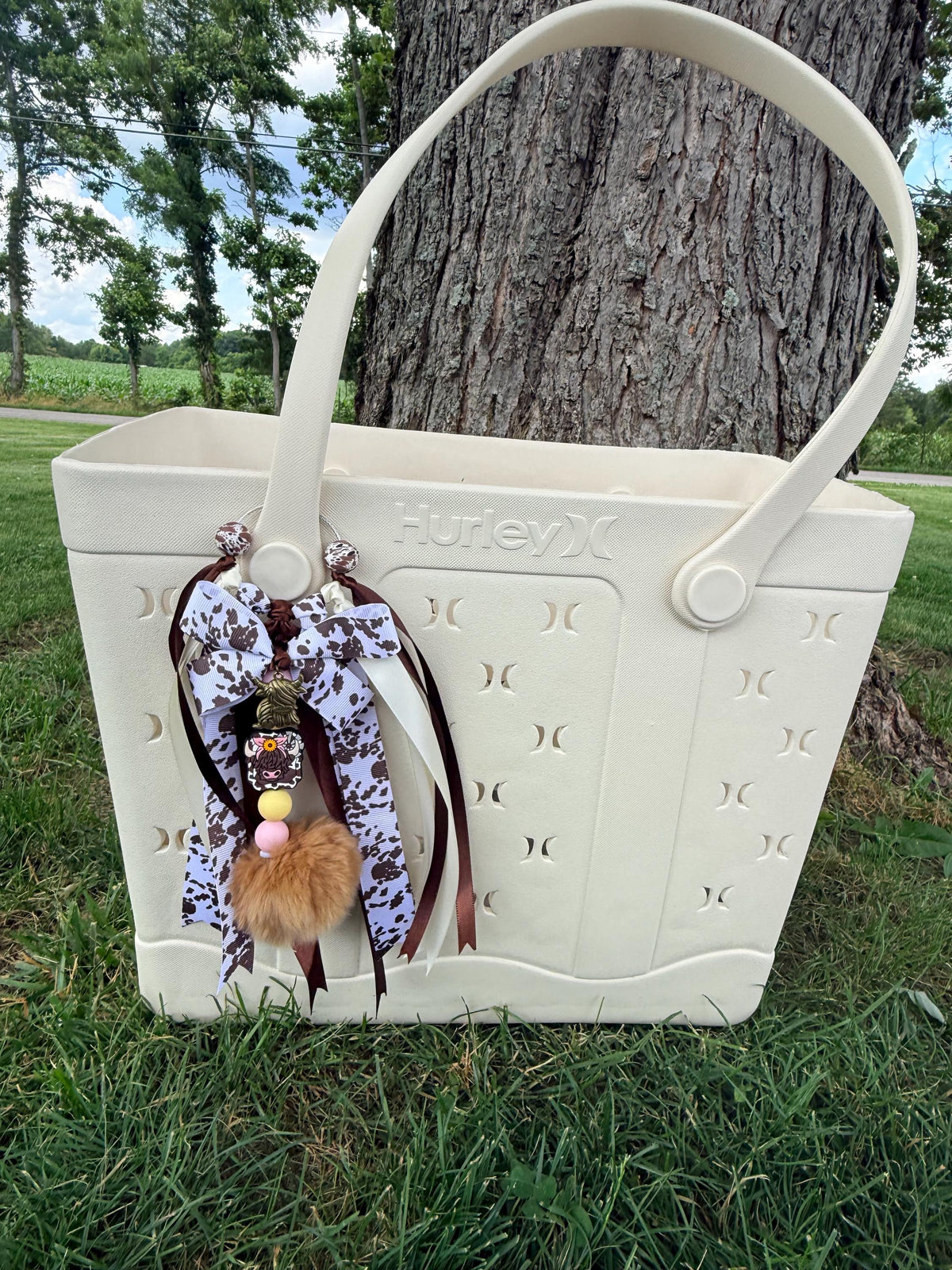 Highland Cow silicone beaded bag tassel with cow print ribbon and silver highland cow charm, featuring brown, white, and cow print beads on a white background
