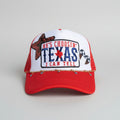 A red and white trucker hat with a white front panel and red mesh back, featuring a decorative embroidered patch that reads TEXAS with a red star and blue lettering. 