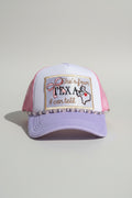A lavender and pink trucker hat with a beaded hat chain and an embroidered front patch with a bow and Texas state outline, 